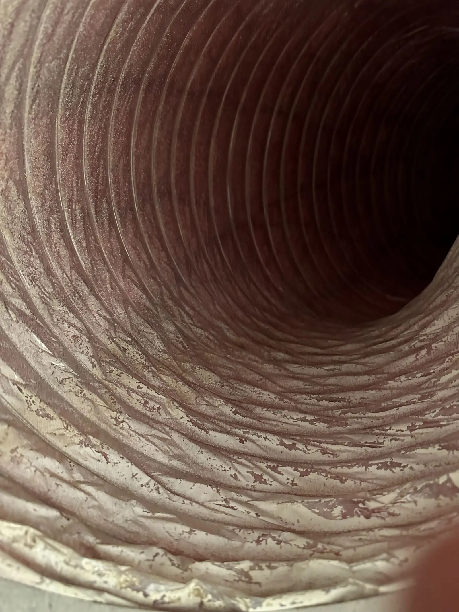 Close view inside ribbed HVAC ductwork showing accumulated debris