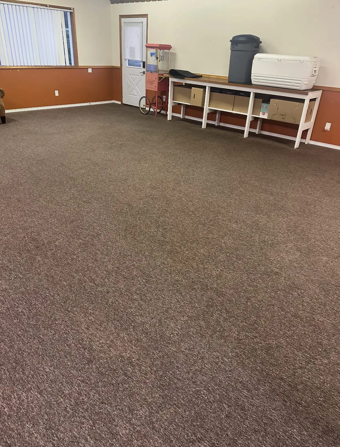The same clubhouse room after cleaning, the brown carpet an even color from wall to wall with the stains gone