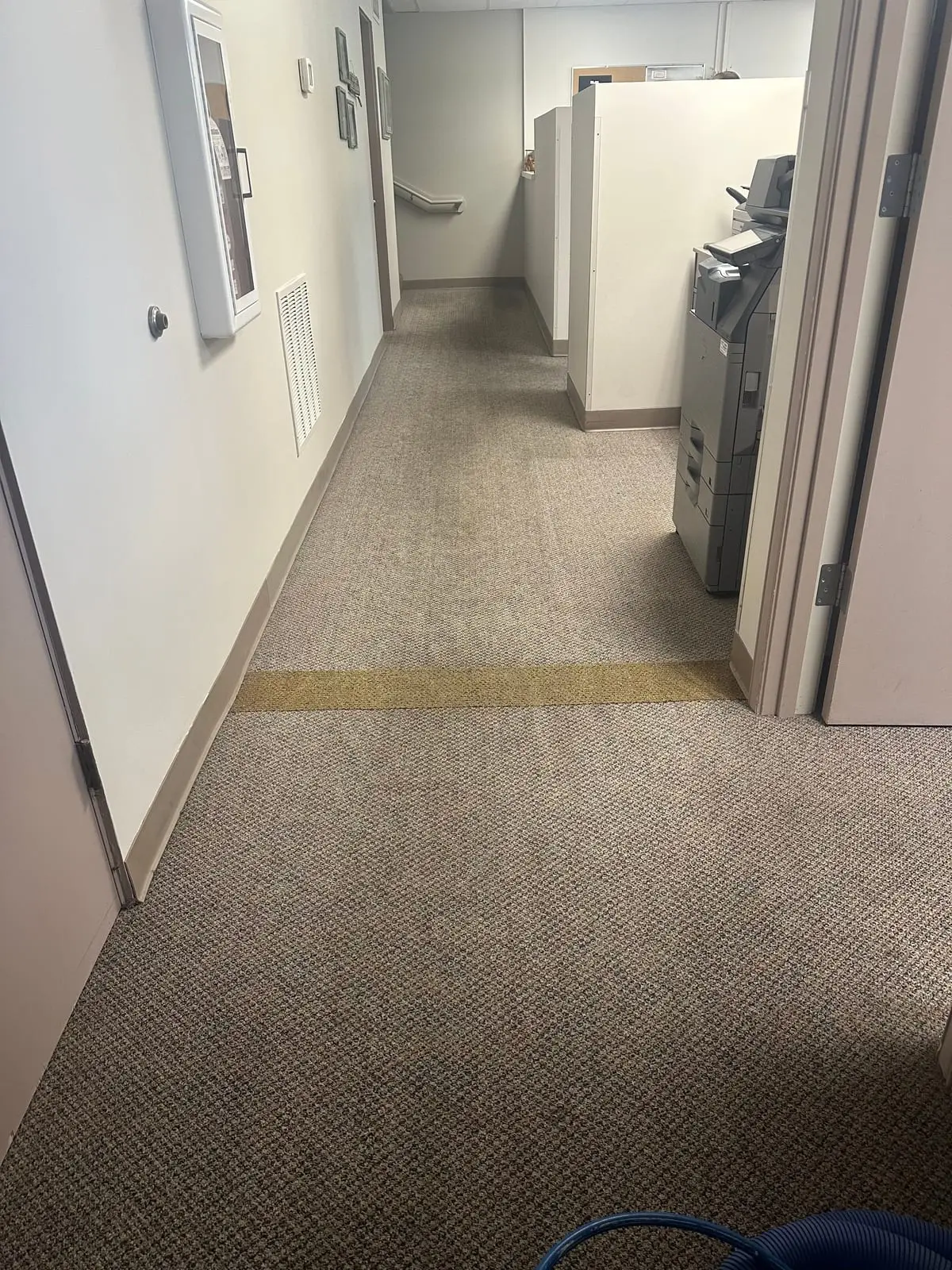 The same office hallway after cleaning, the grey loop carpet an even color from the doorway to the stairs
