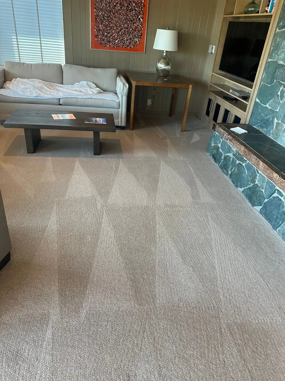 A Freeland living room with freshly cleaned beige carpet showing cleaning strokes, a sofa, coffee table and stone hearth