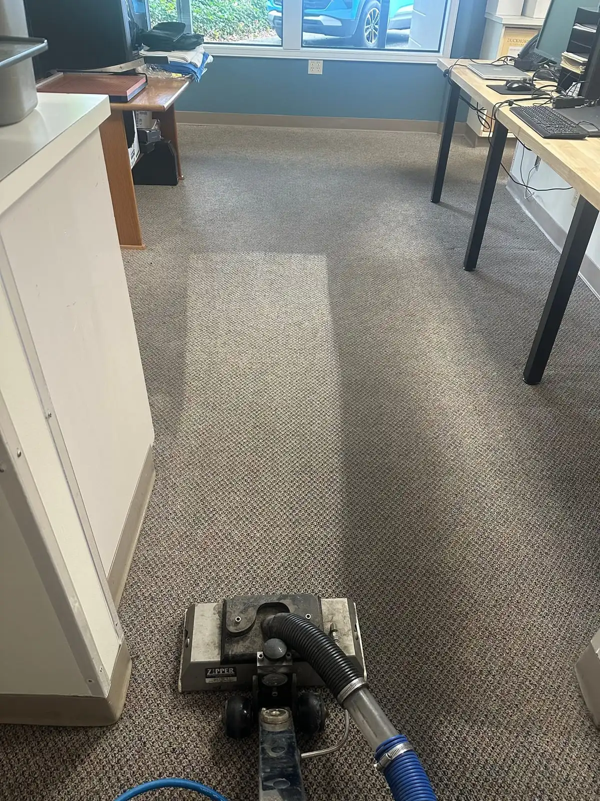 A rotary carpet cleaning tool in an office at Useless Bay Golf & Country Club, with a freshly cleaned lighter stripe running ahead of it
