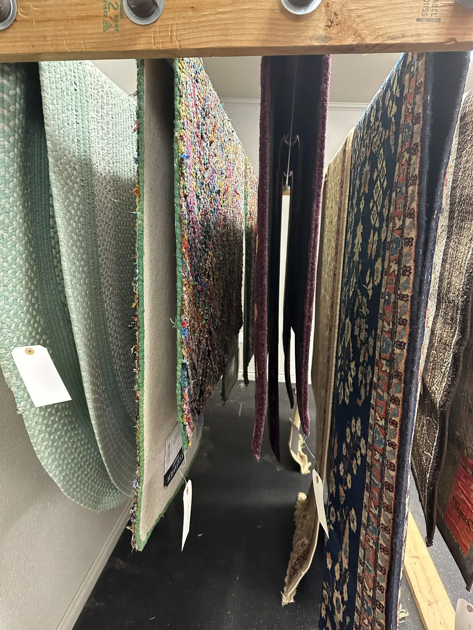 Aisle of the rug cleaning facility with patterned and plain rugs hanging either side