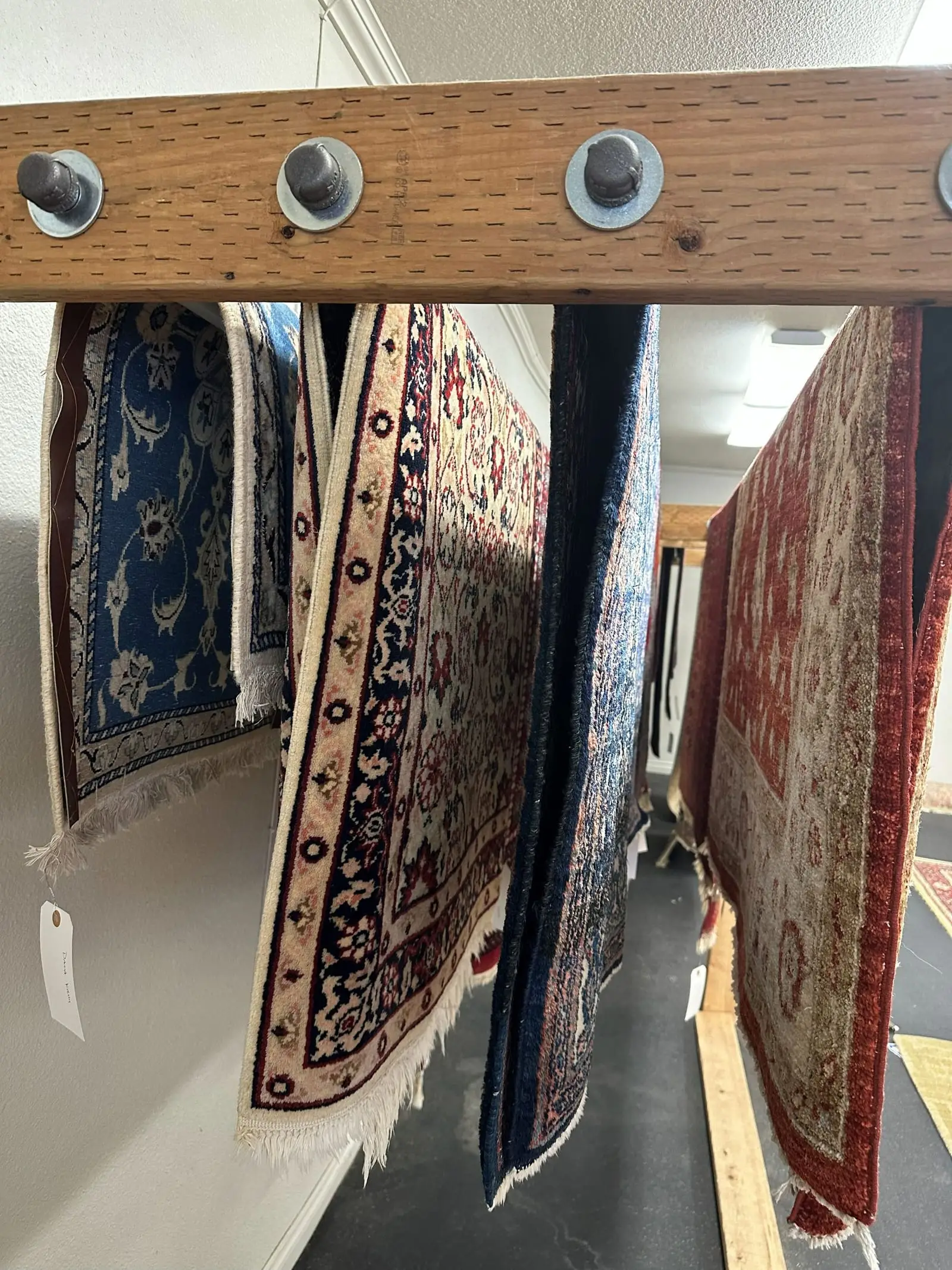 Wool and oriental area rugs hanging on drying racks inside the A Clean Carpet Co rug facility
